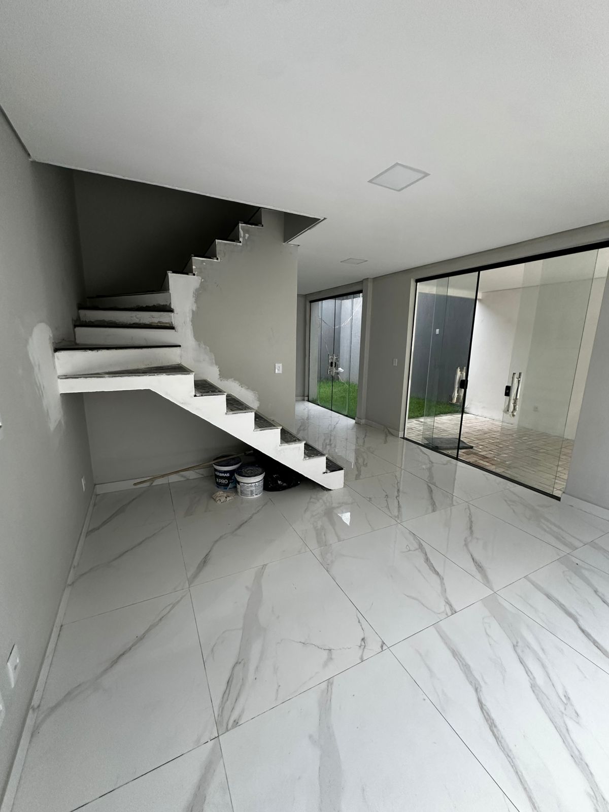 Sky Park: sala ampla com porcelanato marmorizado e escada